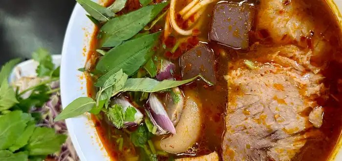 A rich, steaming bowl of Vietnamese noodle soup at Hana Pho, topped with fresh herbs and sliced beef